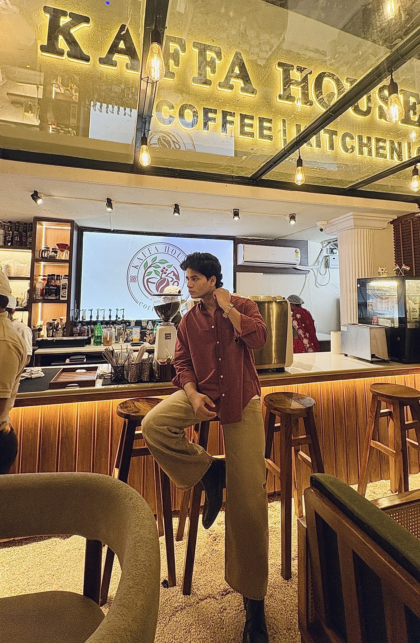 Masud Shaikh seated at Kaffa House cafe, casual look
