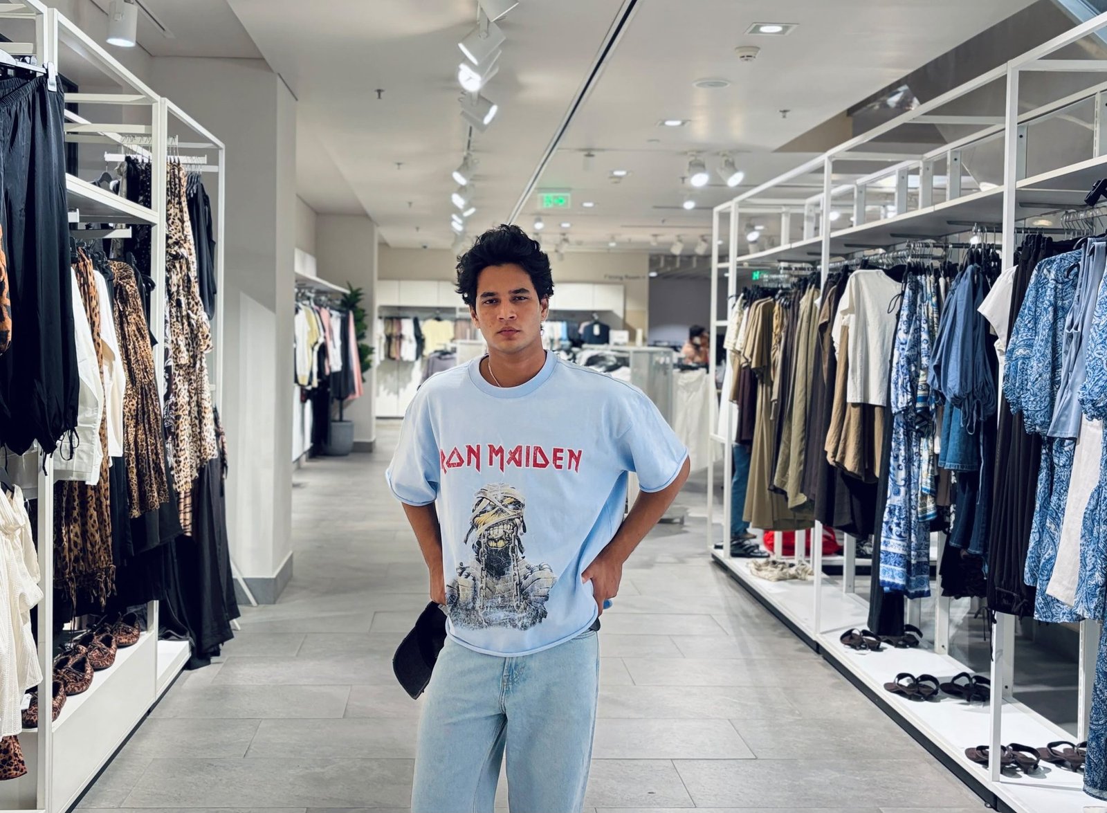 Masud Shaikh wearing an Iron Maiden graphic tee, store aisle